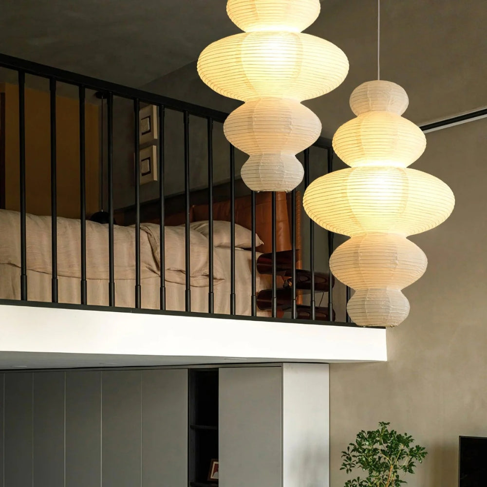 Akari Juni Paper Pendant Light in bedroom, narrow hourglass waist keeping the pleated shade clear of pillows while lighting the nightstand below