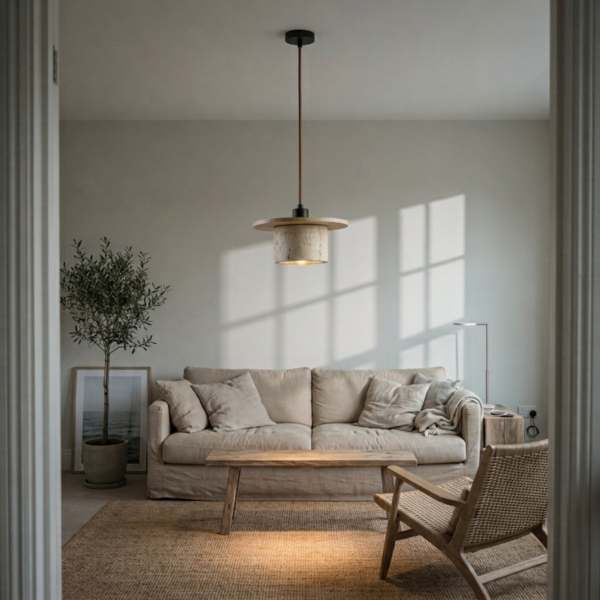Kanso Wabi Sabi Travertine and Wood Pendant Light in living room, compact stone cylinder hung over a reading nook casting a focused warm glow beside the sofa