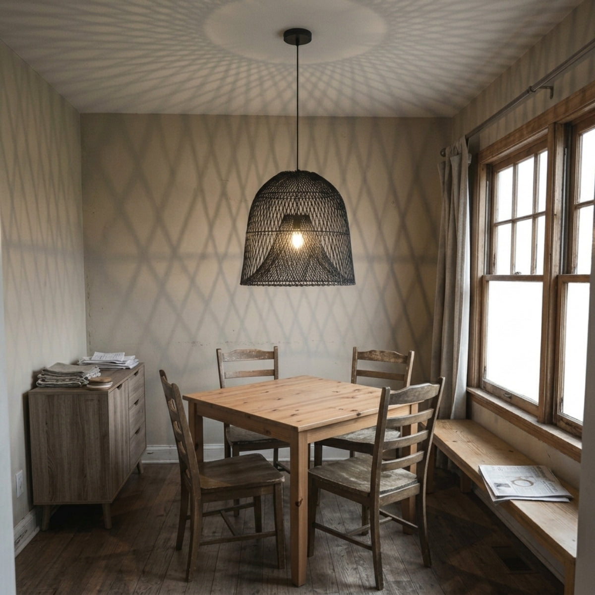 Nassa Black Rattan Pendant above dining table, large size open weave casting light downward without glare across the tabletop surface