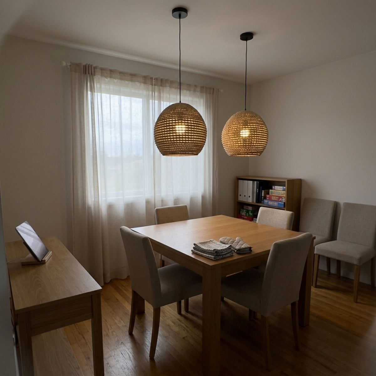 Wekiva Globe Rattan Basket Pendant Light above dining table, dense coil weave spreading even warm light across place settings on a small round table