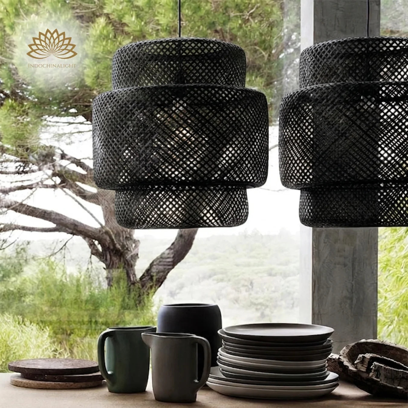 Two large, black Sinnerlig woven bamboo pendant lights hang gracefully above a wooden table set with several ceramic plates and mugs